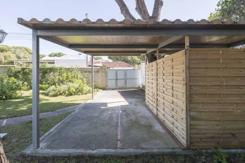 A covered driveway leads to a gate, with a wooden fence along one side.