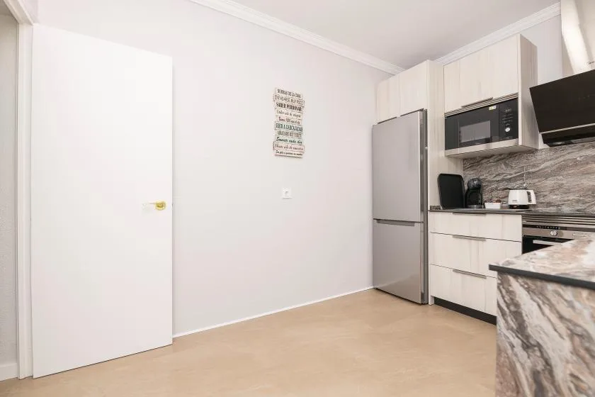 A compact kitchen with a refrigerator, microwave, and light-colored cabinets.
