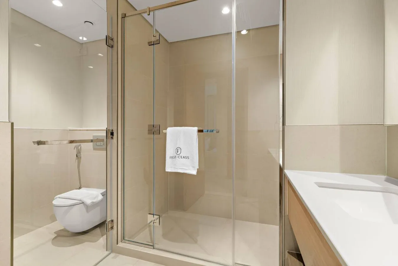 A bright bathroom with a glass shower, toilet, and vanity.