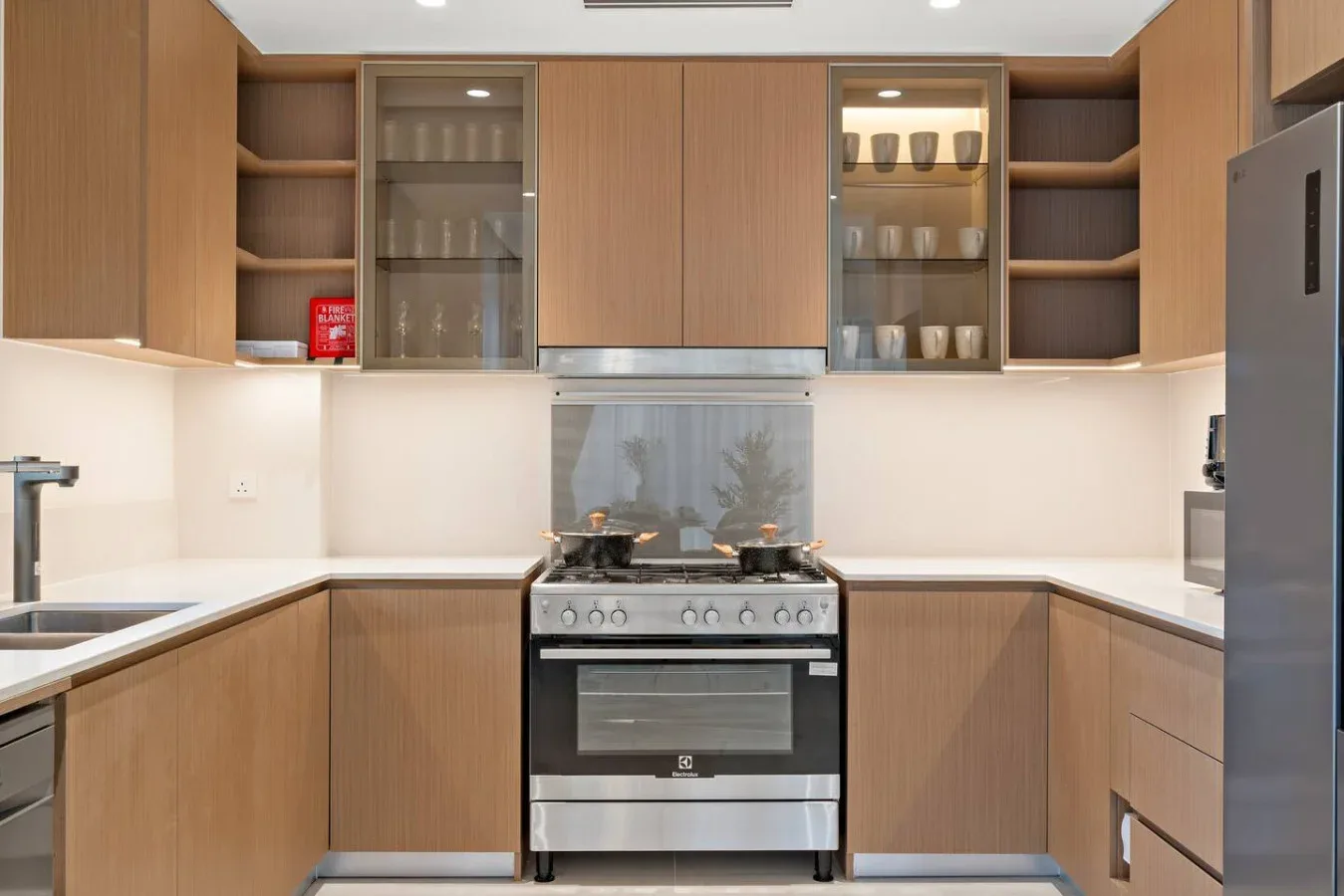 A modern kitchen with wood cabinetry and a stove beneath the upper cabinets.
