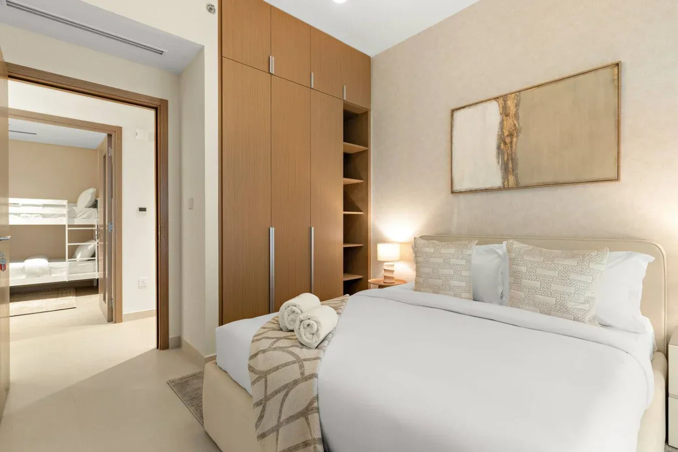 A bedroom with a neatly made bed, wooden cabinetry, and a framed artwork.