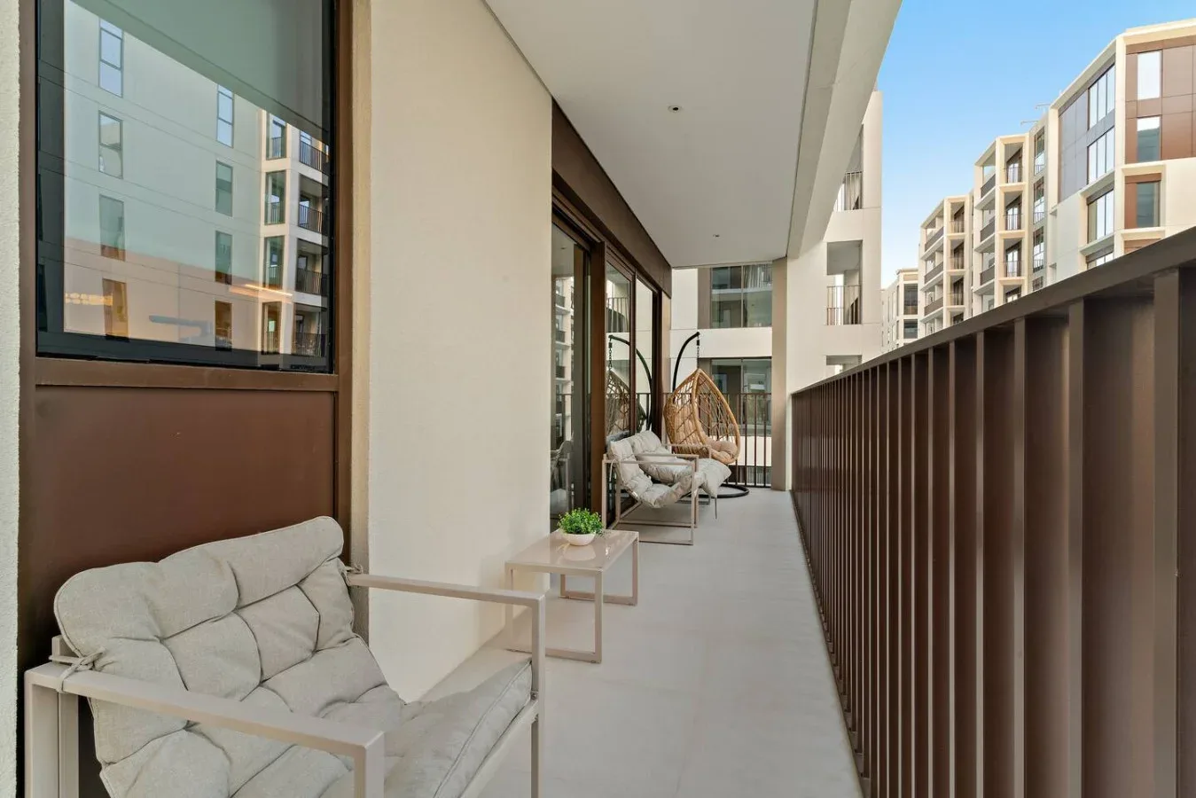 A balcony seating area overlooks neighboring apartment buildings.