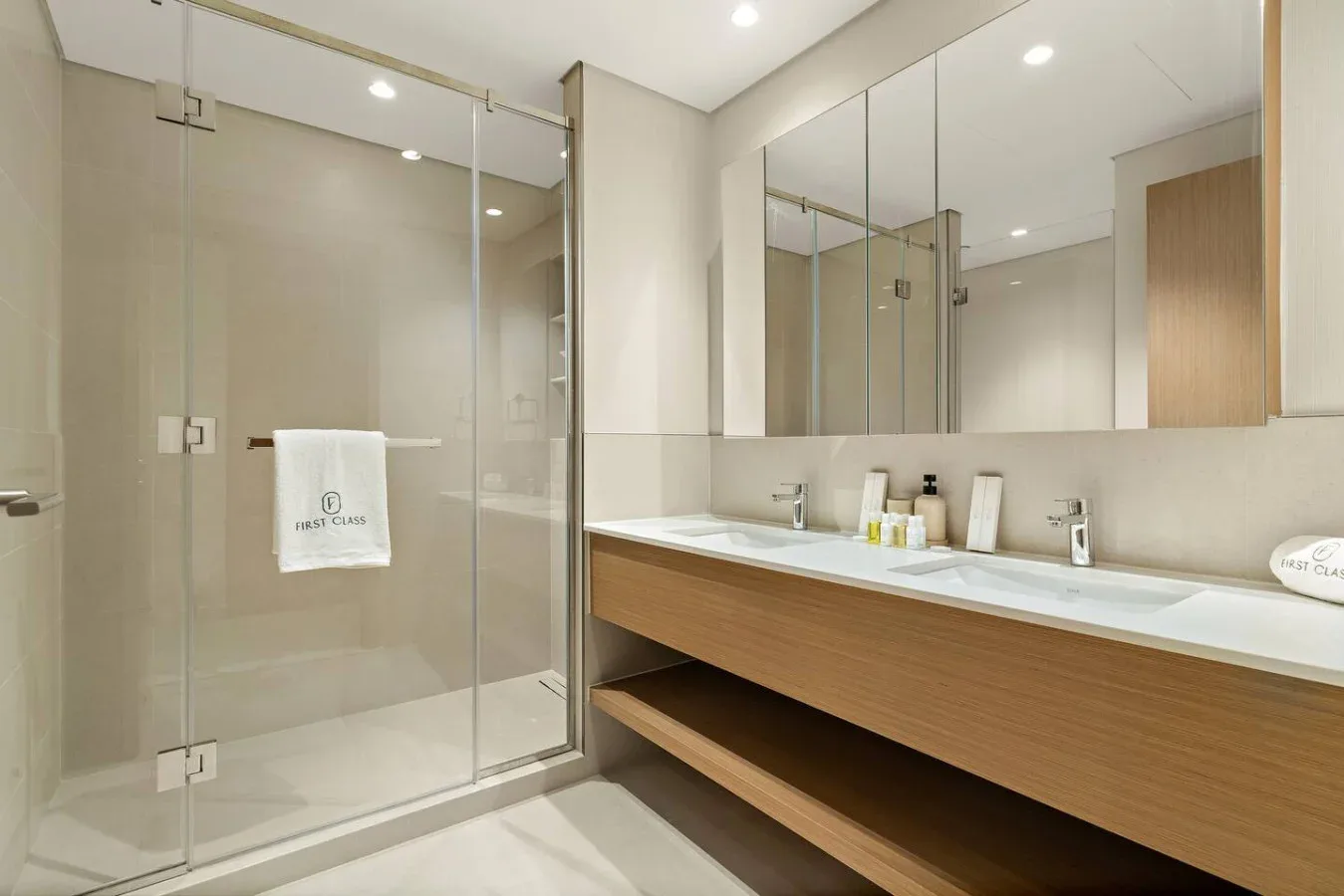 A modern bathroom with a glass shower and a long vanity beneath a mirror.