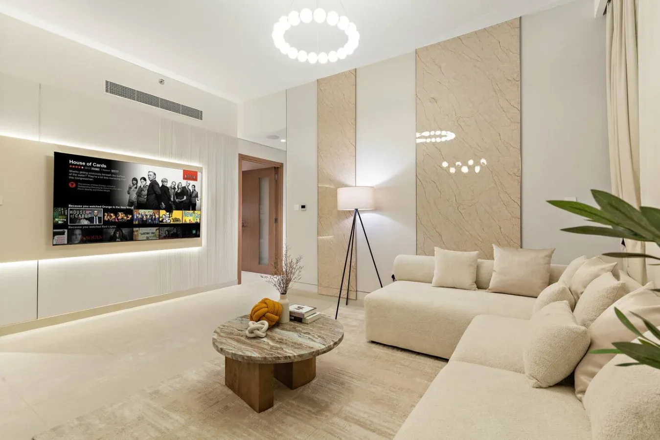 A bright living room with a light-colored sectional and a round coffee table.