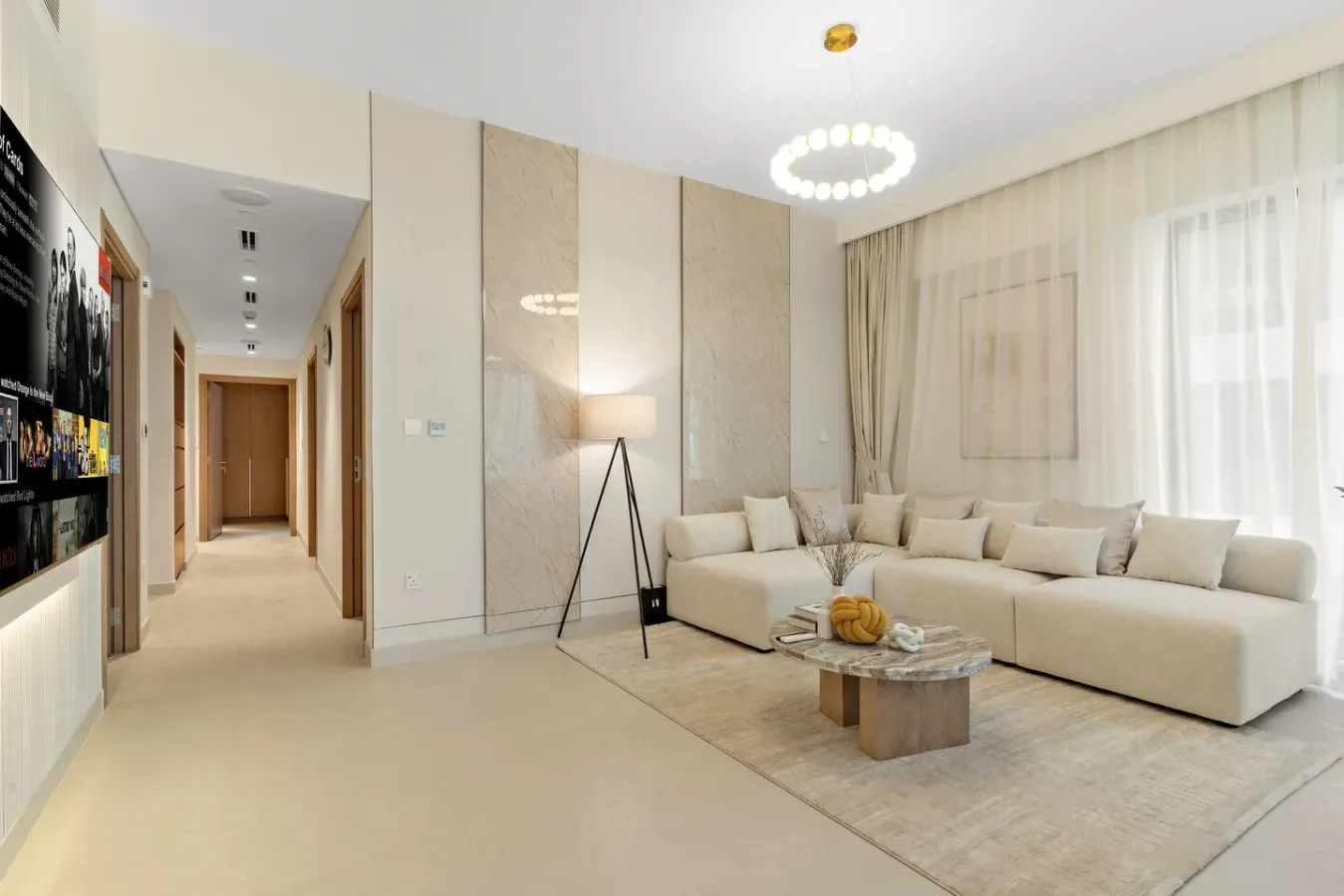 A bright living room with a sectional seating area beside a hallway.