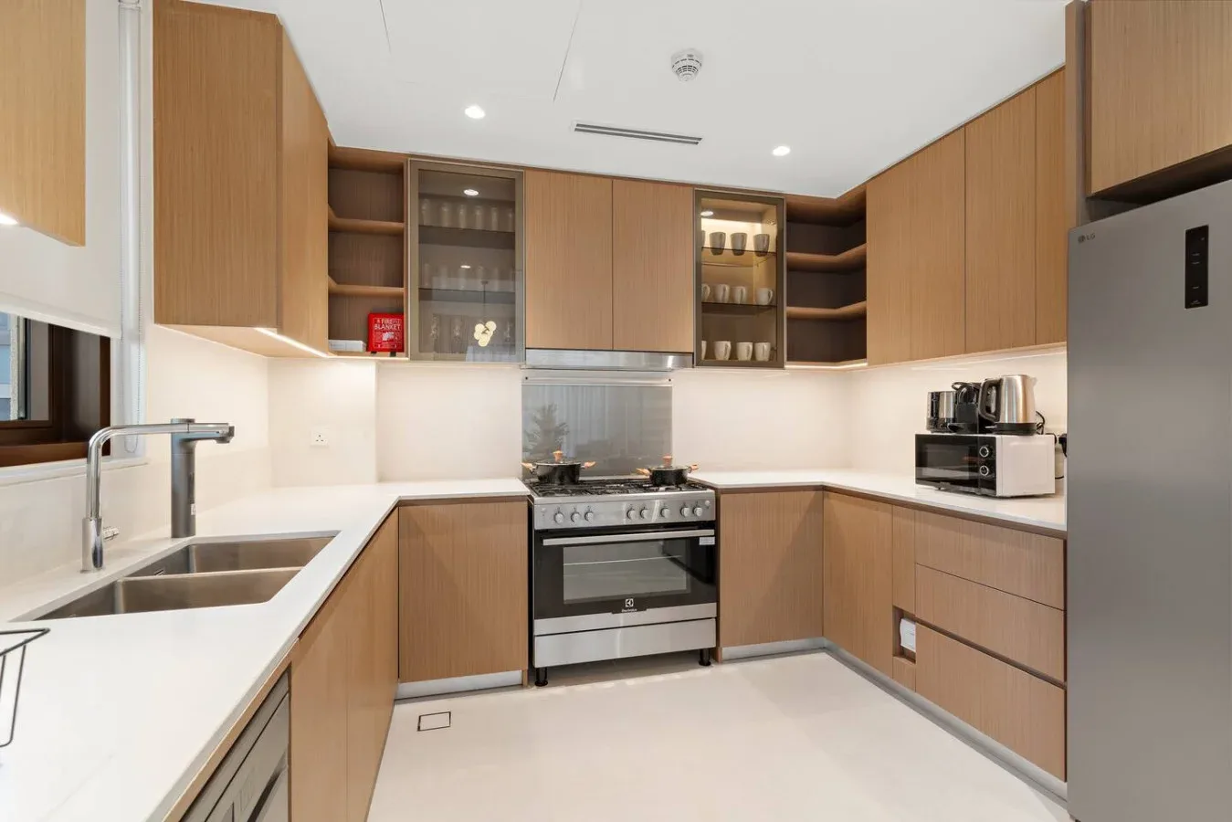 A modern kitchen with wood cabinets, white countertops, and a stove.