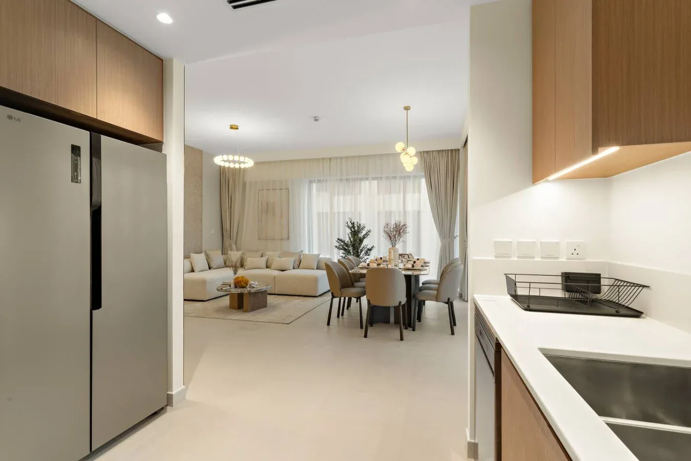 An open-plan kitchen and dining area overlooks a living room with floor-to-ceiling curtains.