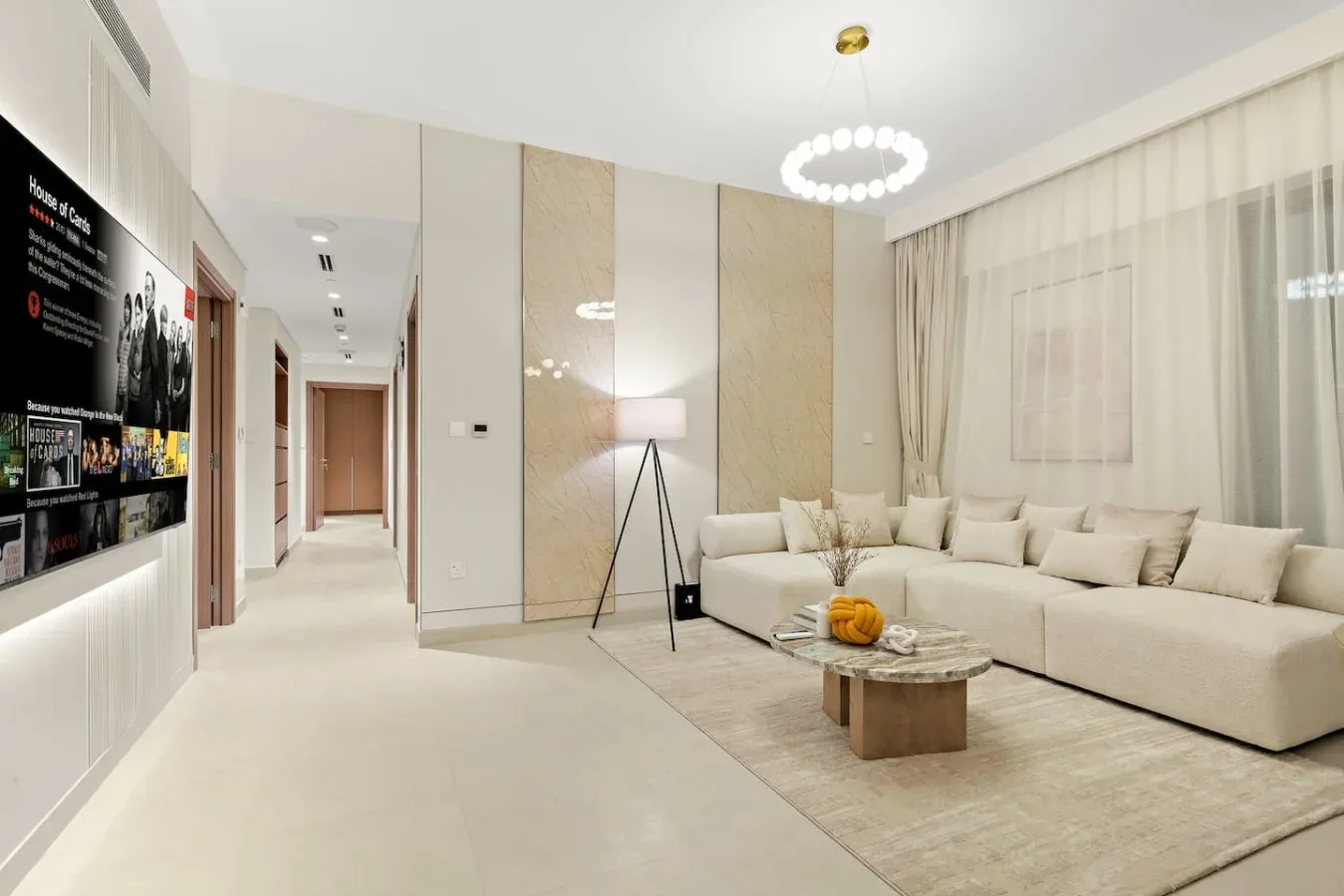 A bright living room with pale seating, a low coffee table, and a hallway.