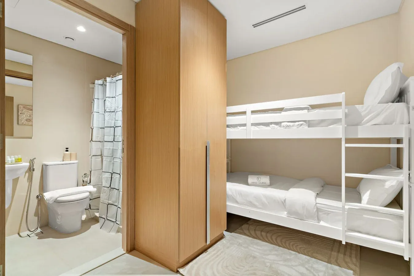 A compact sleeping area with bunk beds beside a bathroom with a shower and toilet.