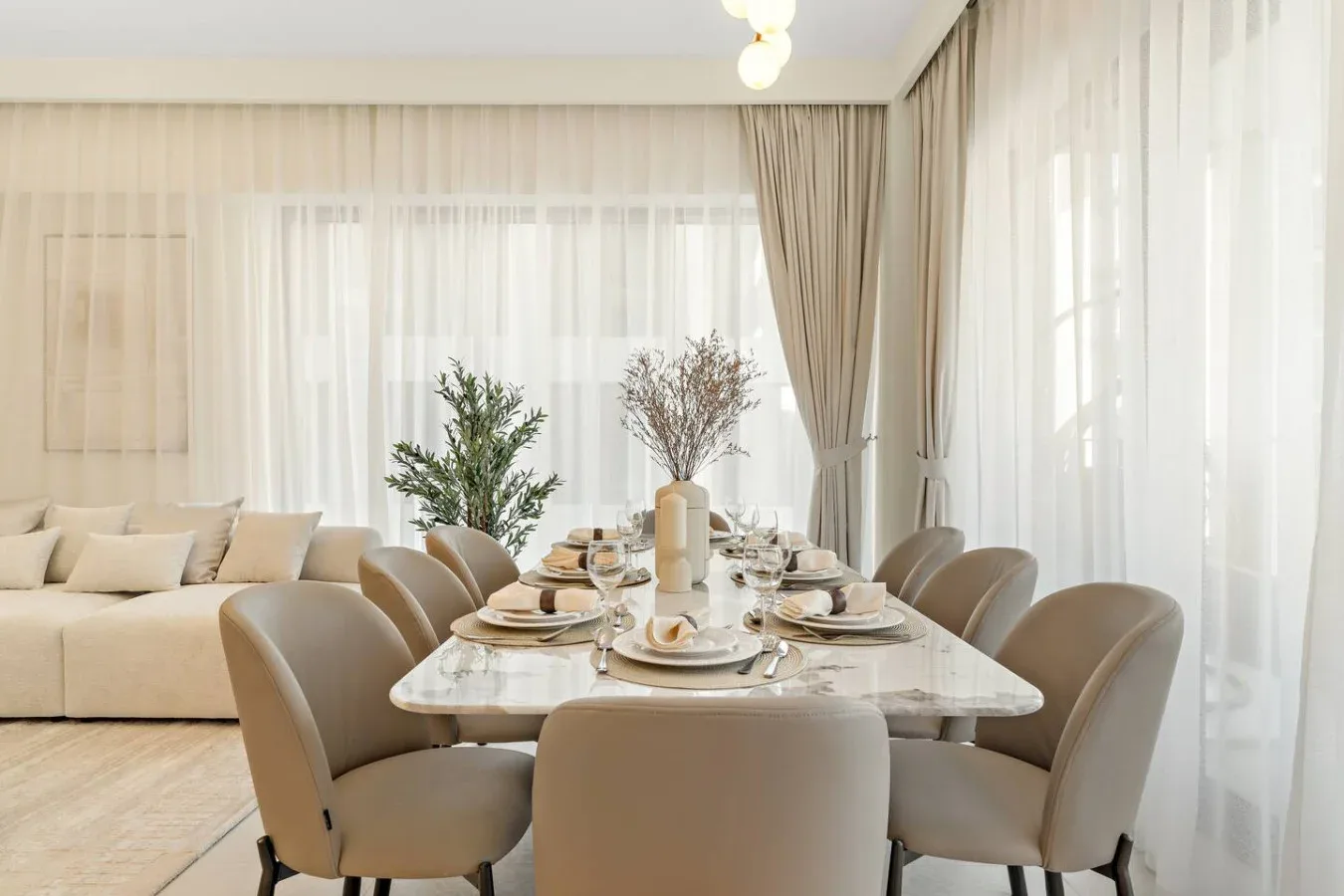 A bright dining area with a set table beside a living room seating area.