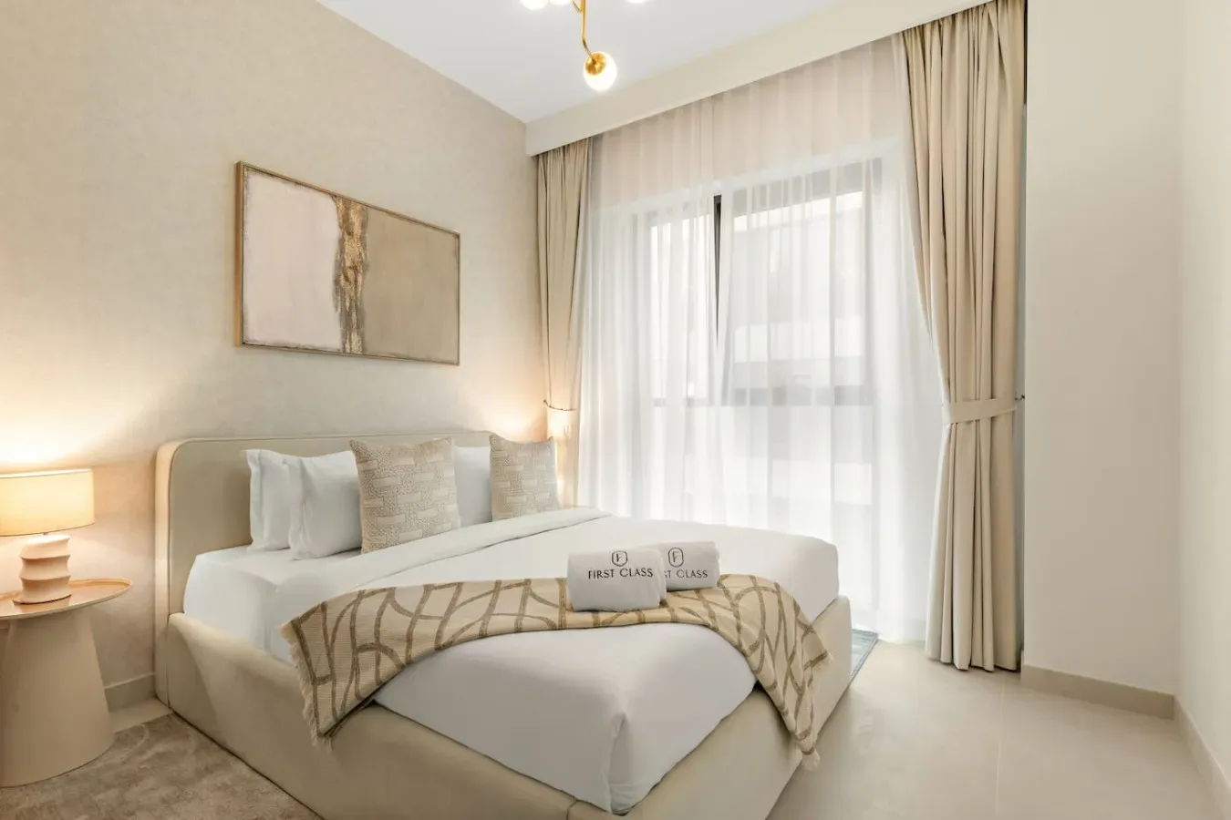 A bedroom with a bed, bedside lamps, and curtains over a large window.