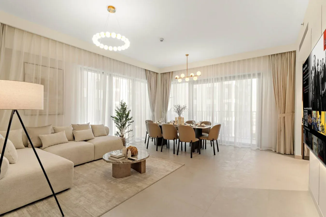 A bright living and dining room with seating, a dining table, and large windows.