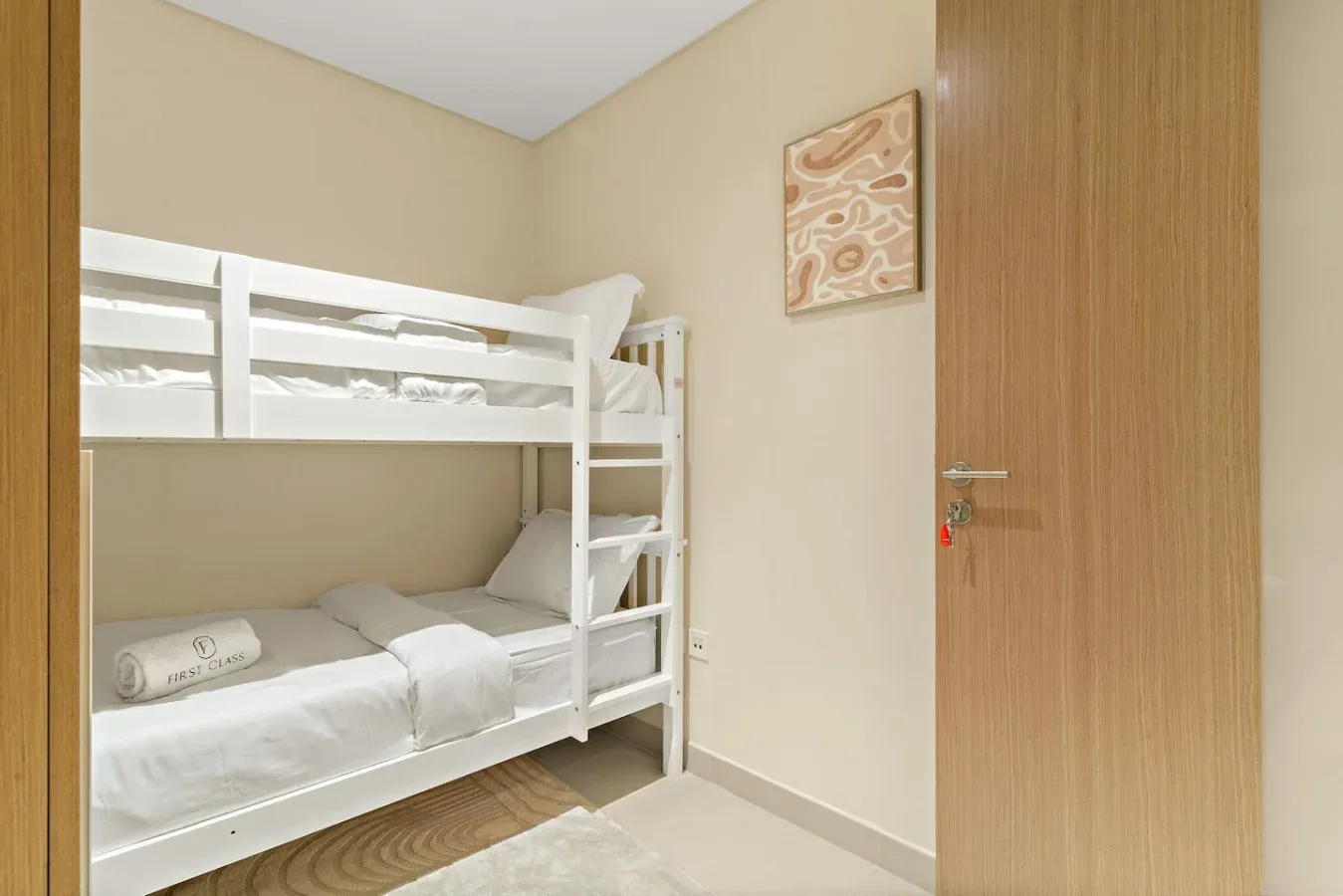 A bedroom with a white bunk bed and framed artwork on the wall.