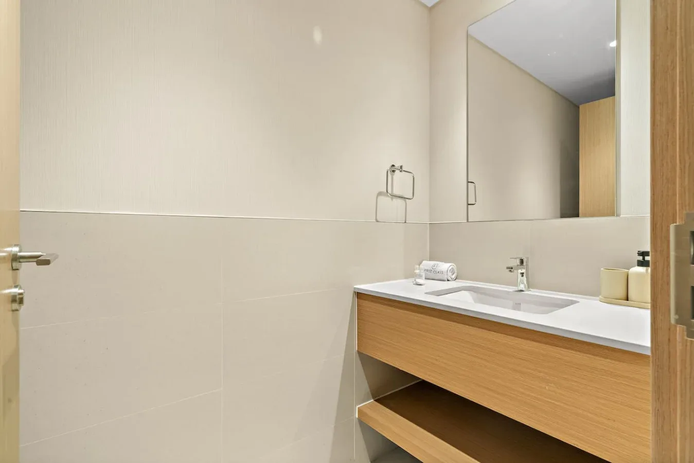 A bathroom vanity with a wide mirror and open wooden shelving.