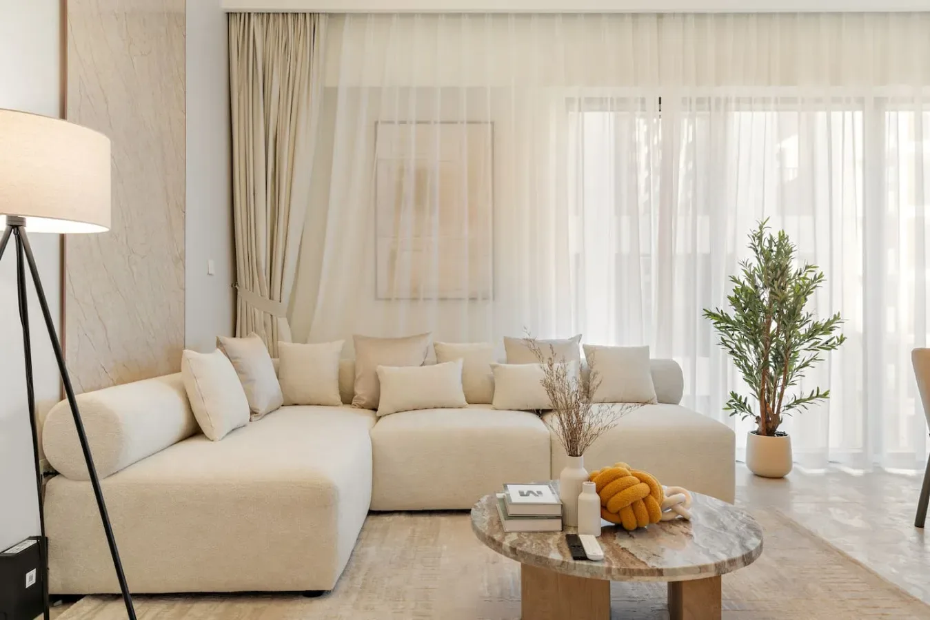 A bright living room with a cream sectional and a round coffee table.