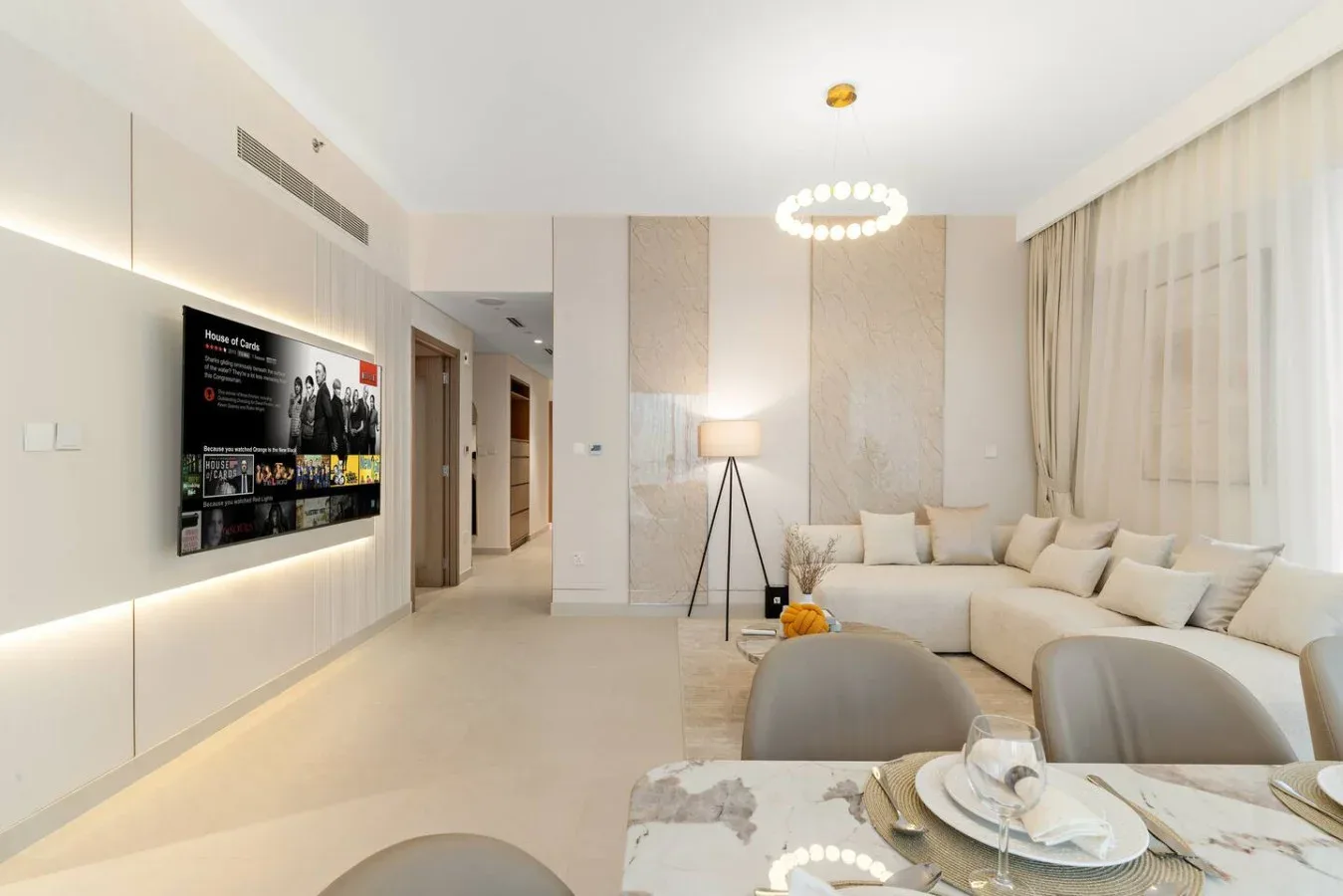 A bright living room with a sectional sofa, television, and floor lamp.
