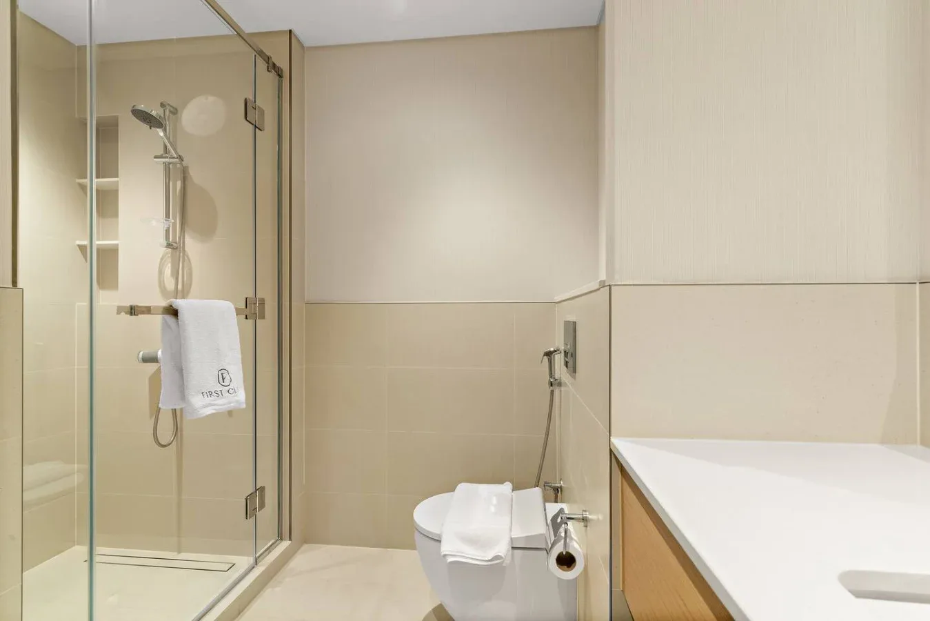 A bathroom with a glass shower, toilet, and countertop.
