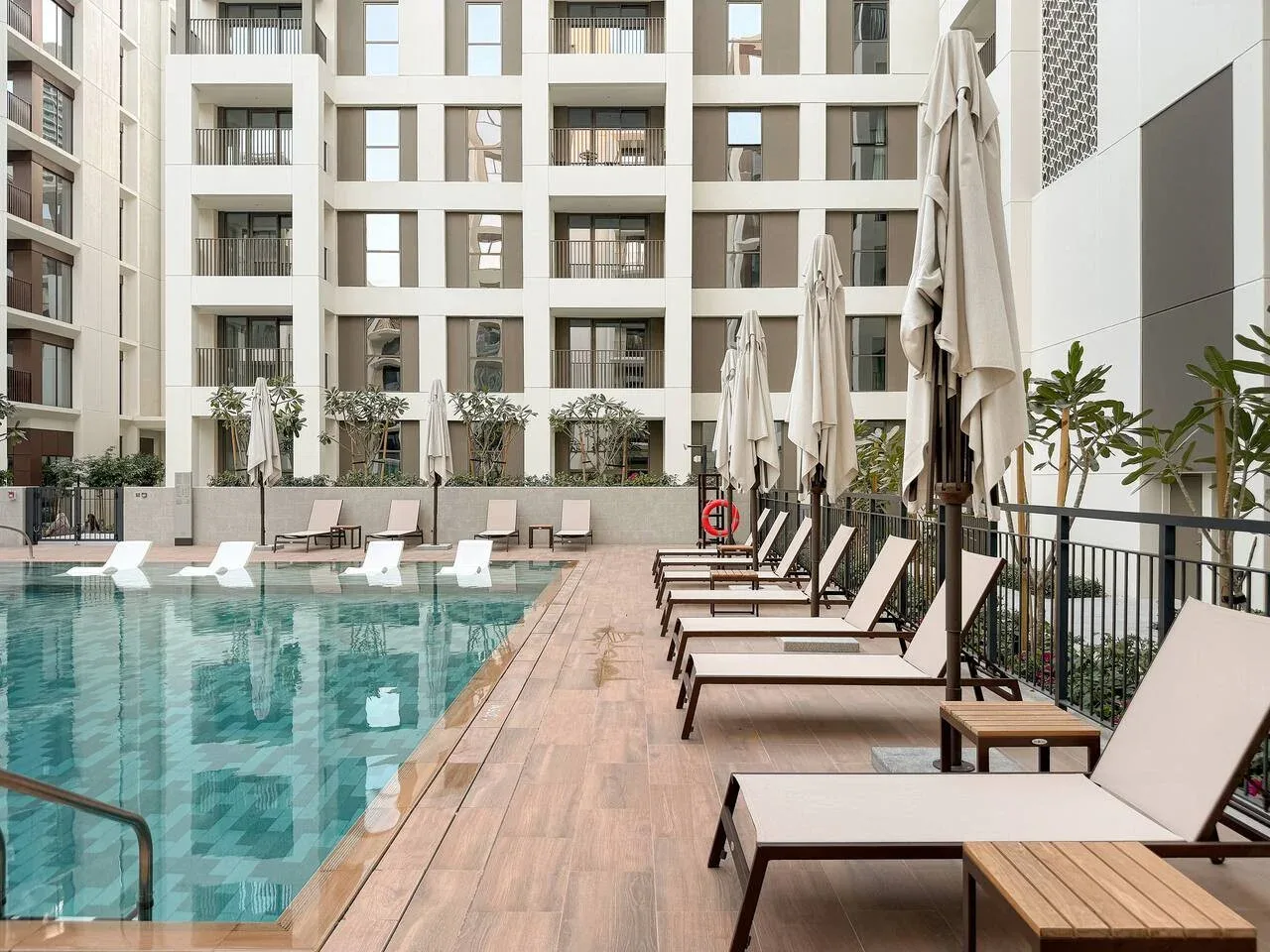 An outdoor swimming pool beside a deck with rows of loungers.