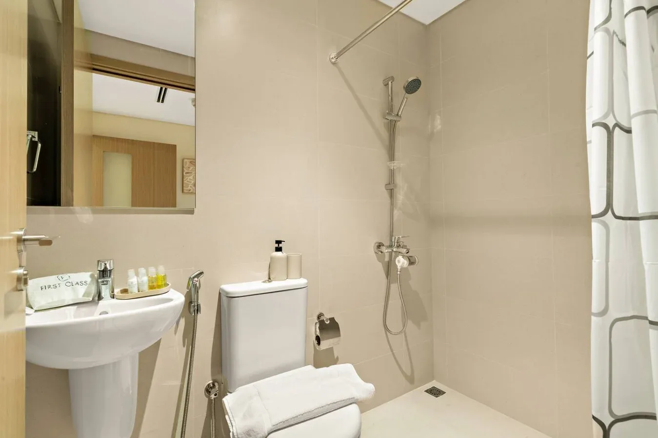 A bathroom with a sink, mirror, toilet, and shower.