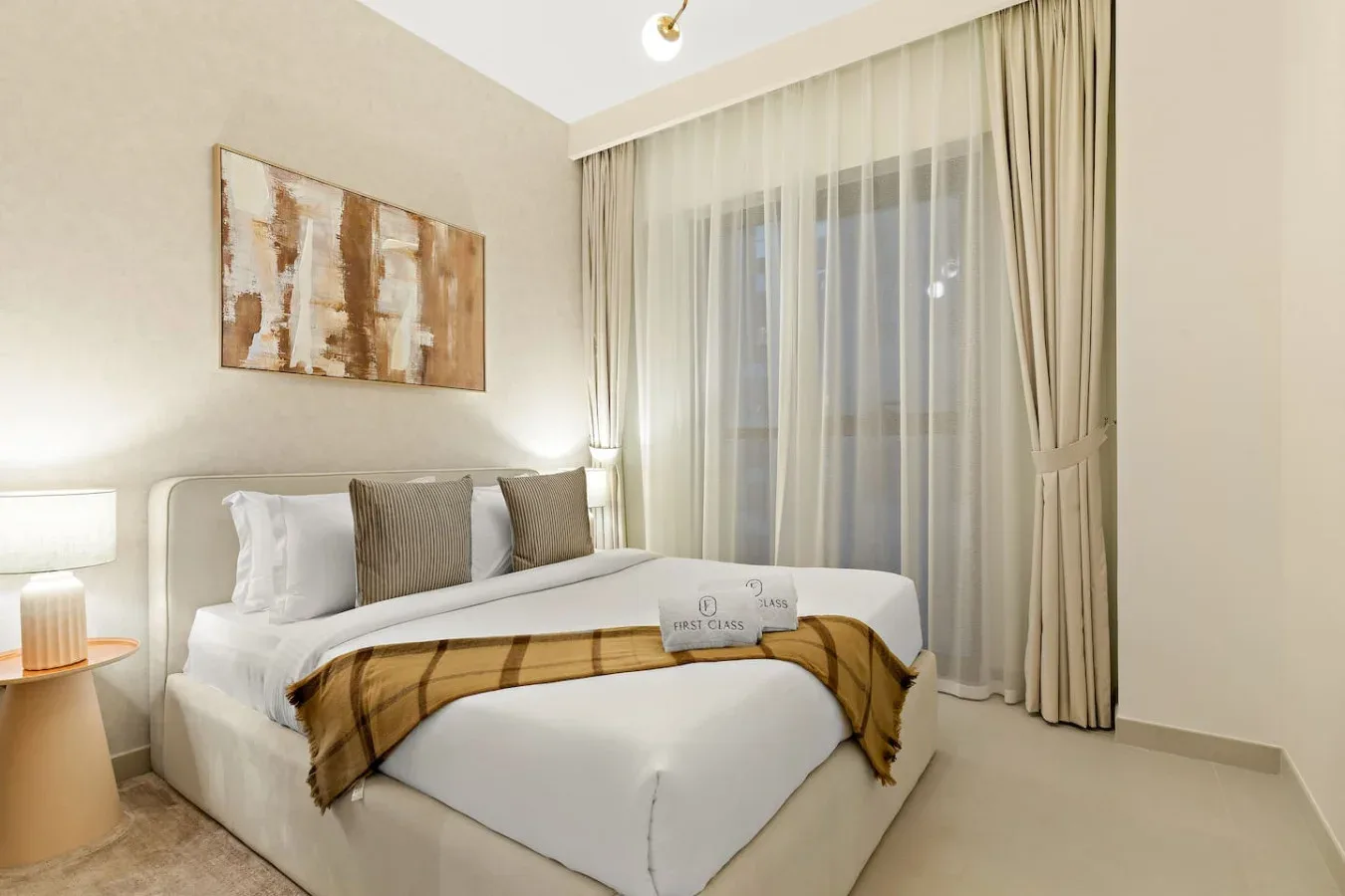 A bedroom with a neatly made bed, decorative pillows, and curtains over the window.