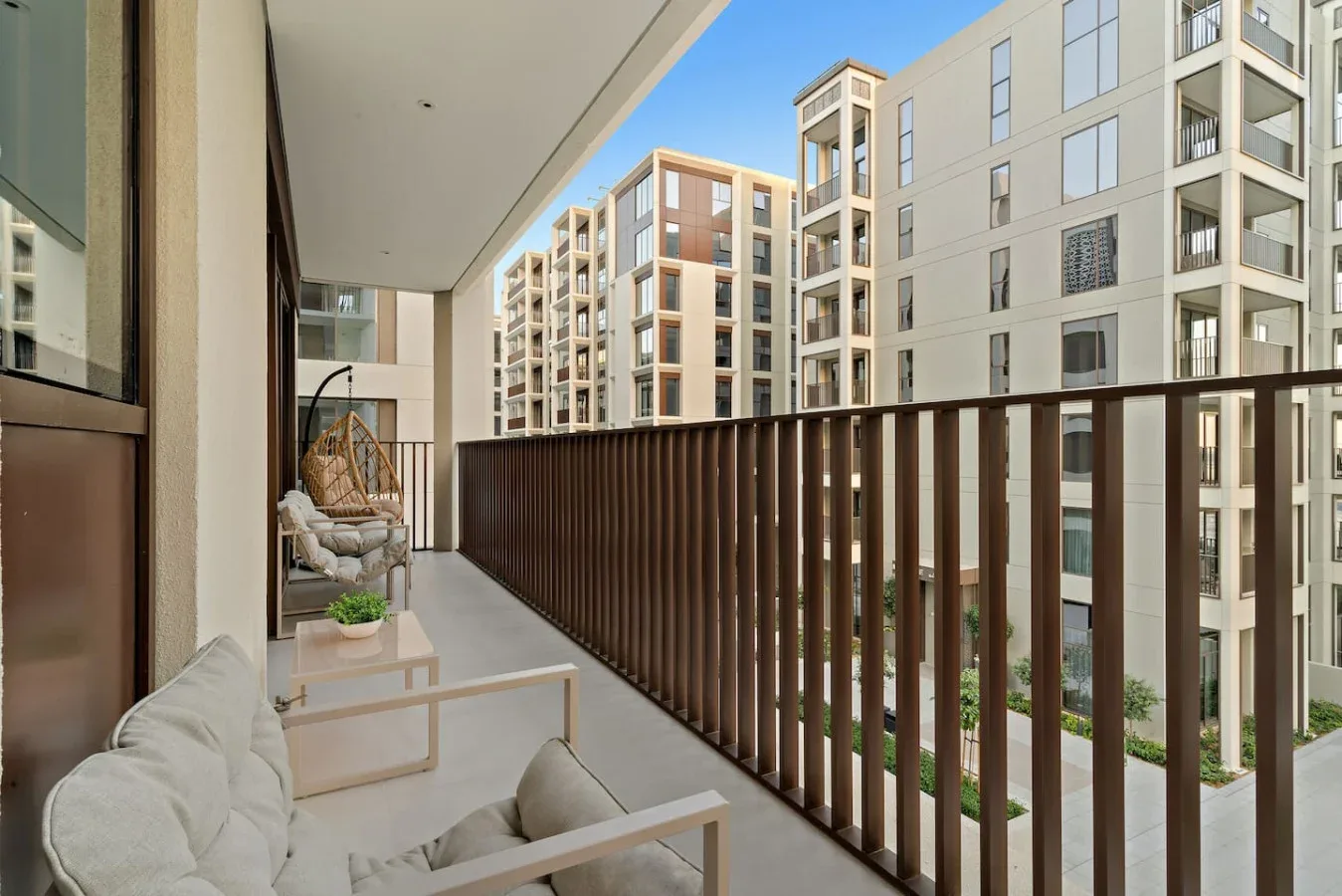 A covered balcony with seating overlooks a courtyard of apartment buildings.