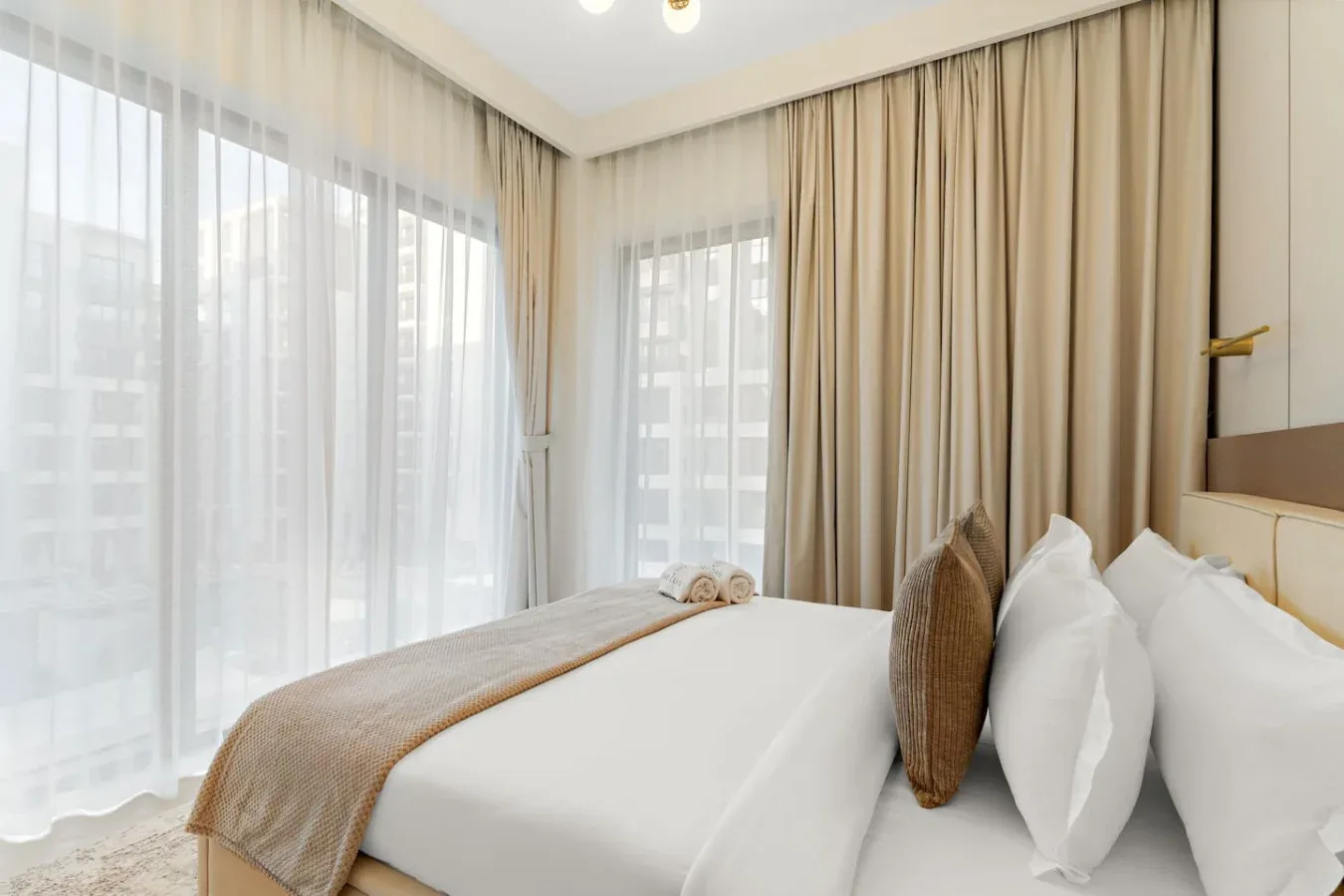 A bedroom with a neatly made bed and curtains over the windows.