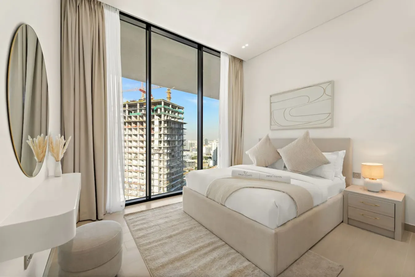 A bright bedroom with a neatly made bed beside large windows.