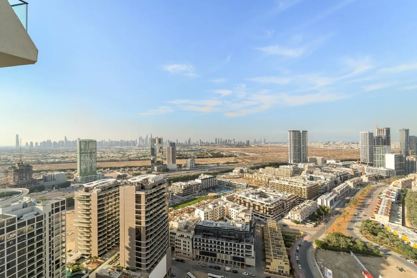 A cityscape viewed from above, with high-rise buildings and a broad blue sky.