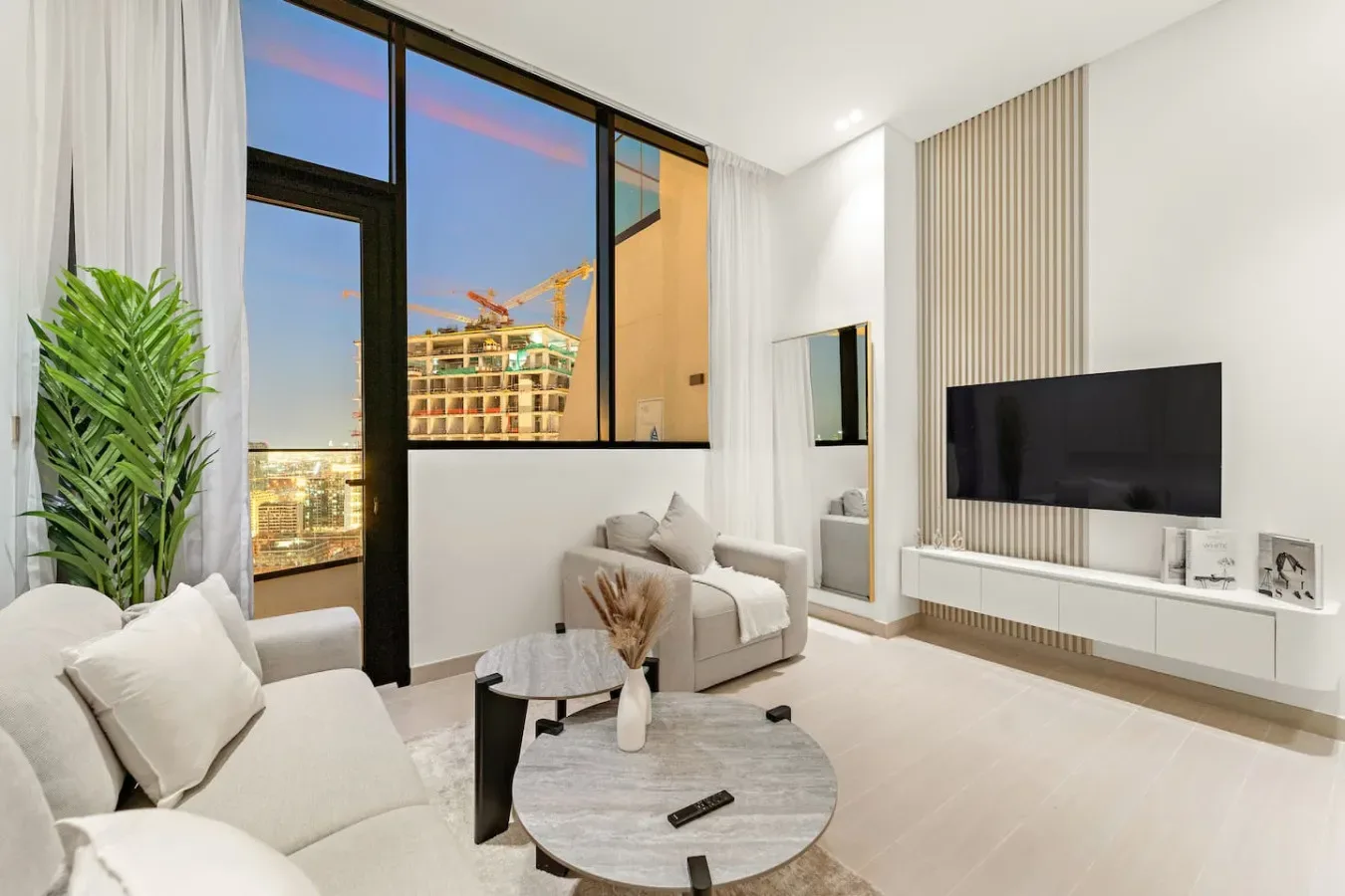 A bright living room with seating, a television, and large windows.