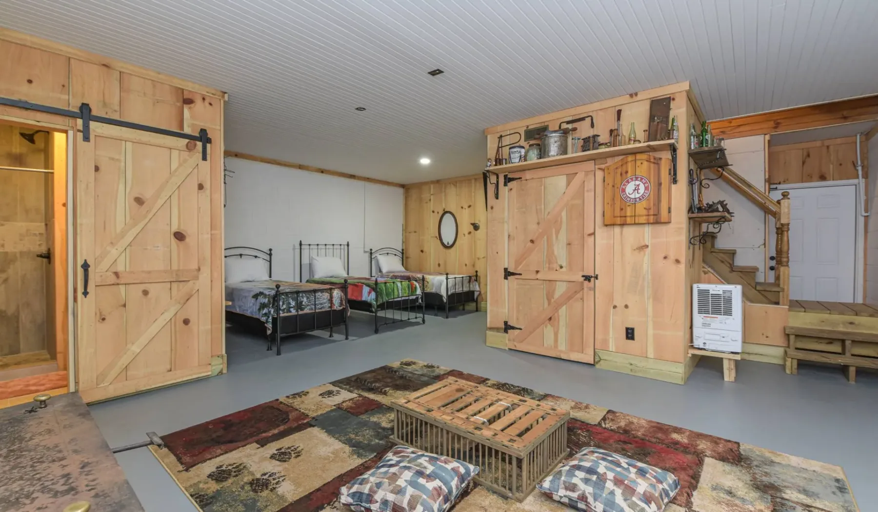 A rustic bedroom with several beds, wooden partitions, and a patterned rug.