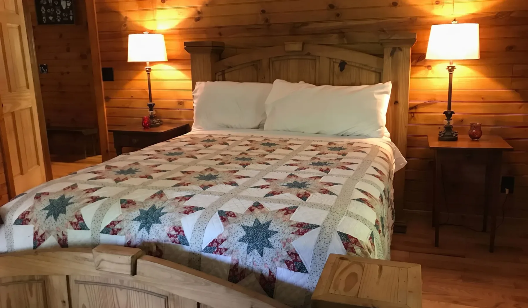 A bedroom with a wooden bed, white pillows, and a patterned quilt.