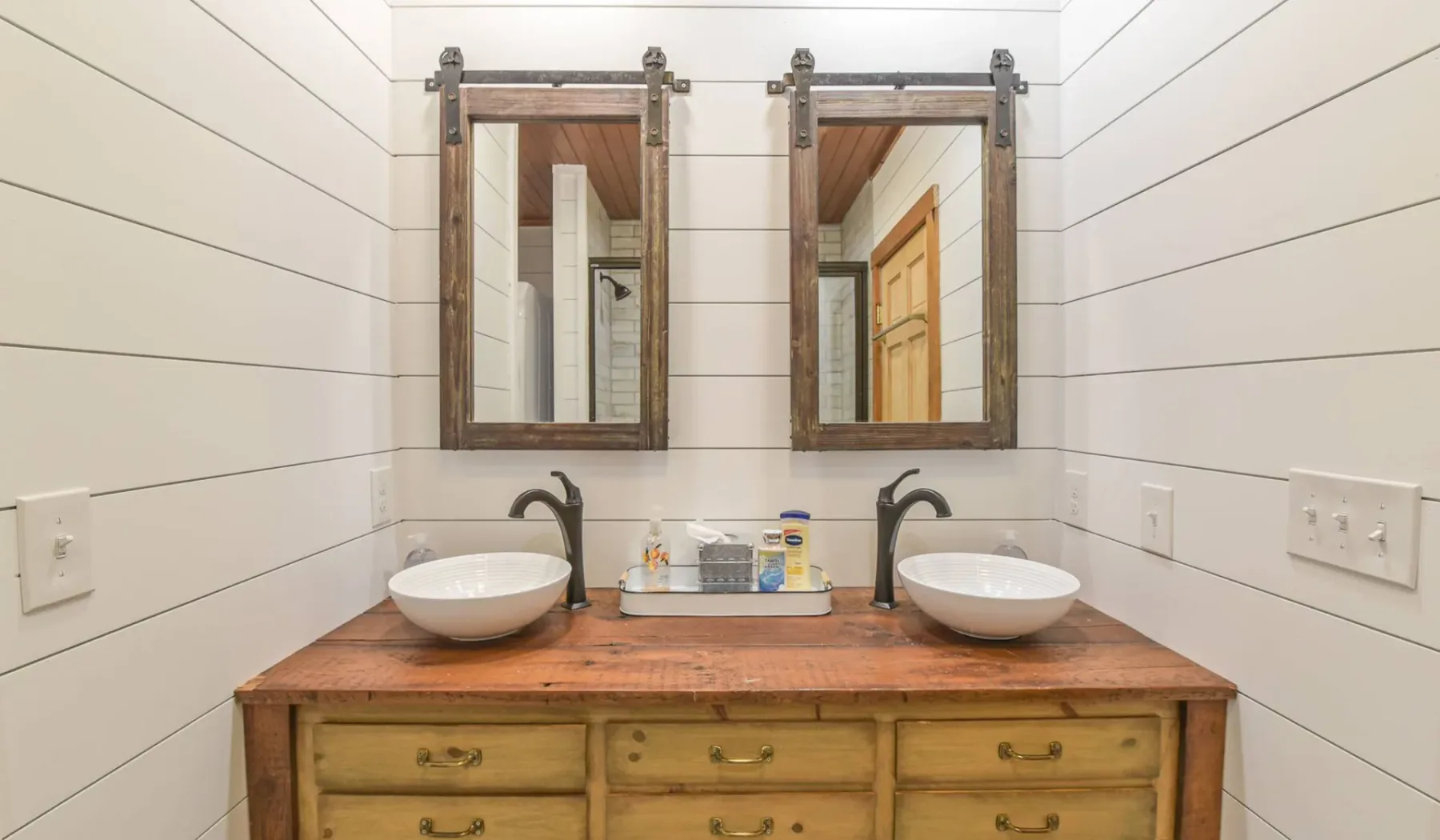 A bathroom vanity with two sinks sits beneath a pair of mirrors.