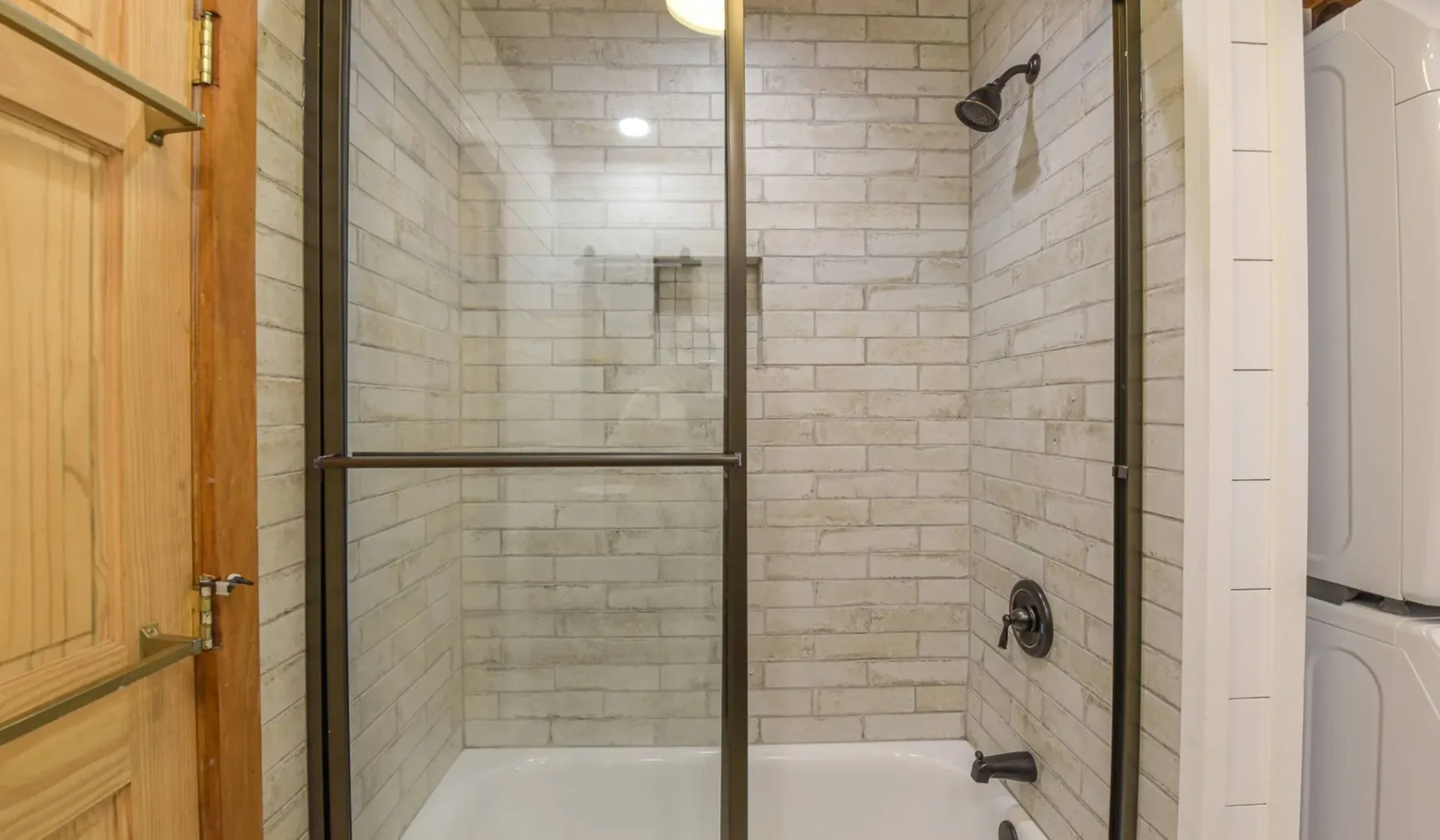 A tiled bathroom shower with a glass partition and visible shower fixtures.