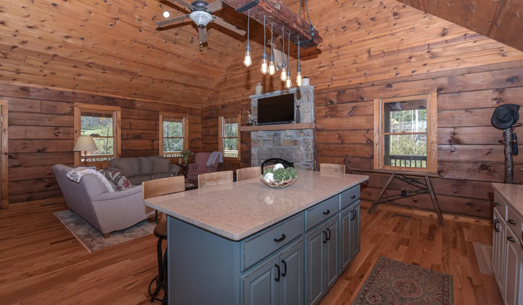 Cocina y sala con paneles de madera, una isla central y una chimenea de piedra.