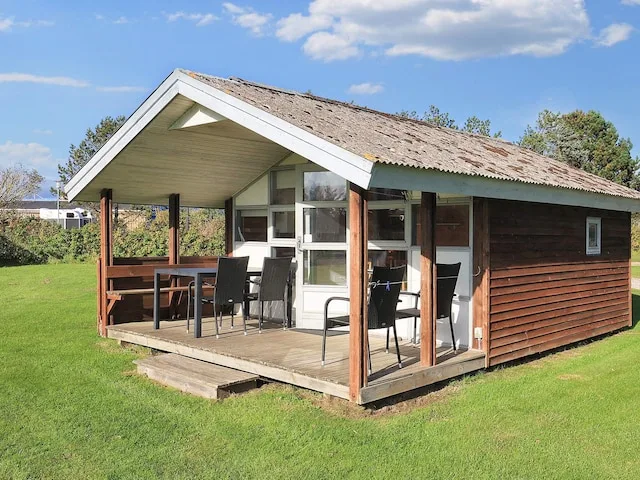 A wooden holiday cottage with a covered patio and outdoor seating.