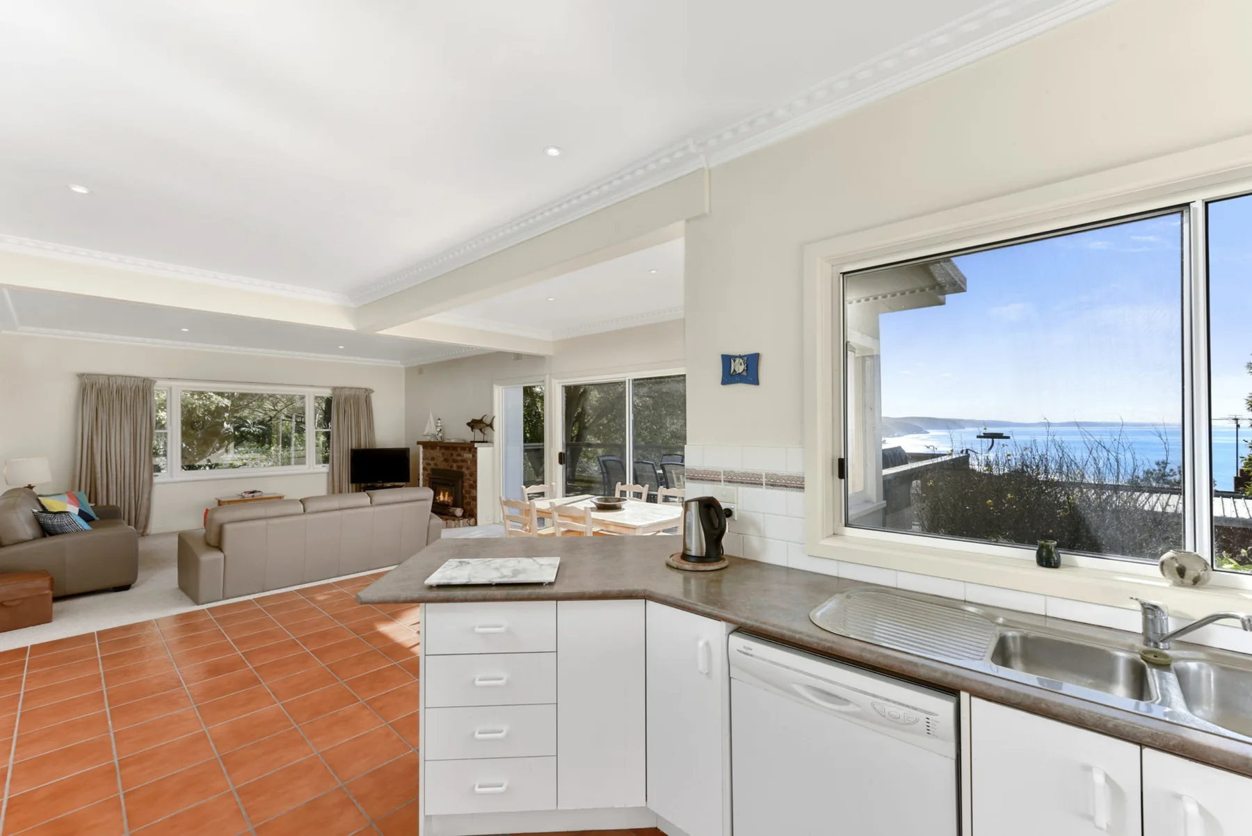 A bright open-plan living room and kitchen with a wide ocean view.