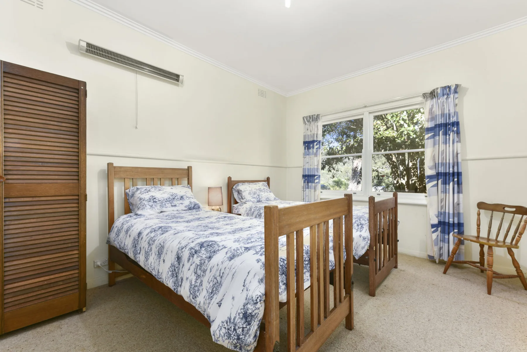 Un dormitorio luminoso con camas de madera y una ventana grande.