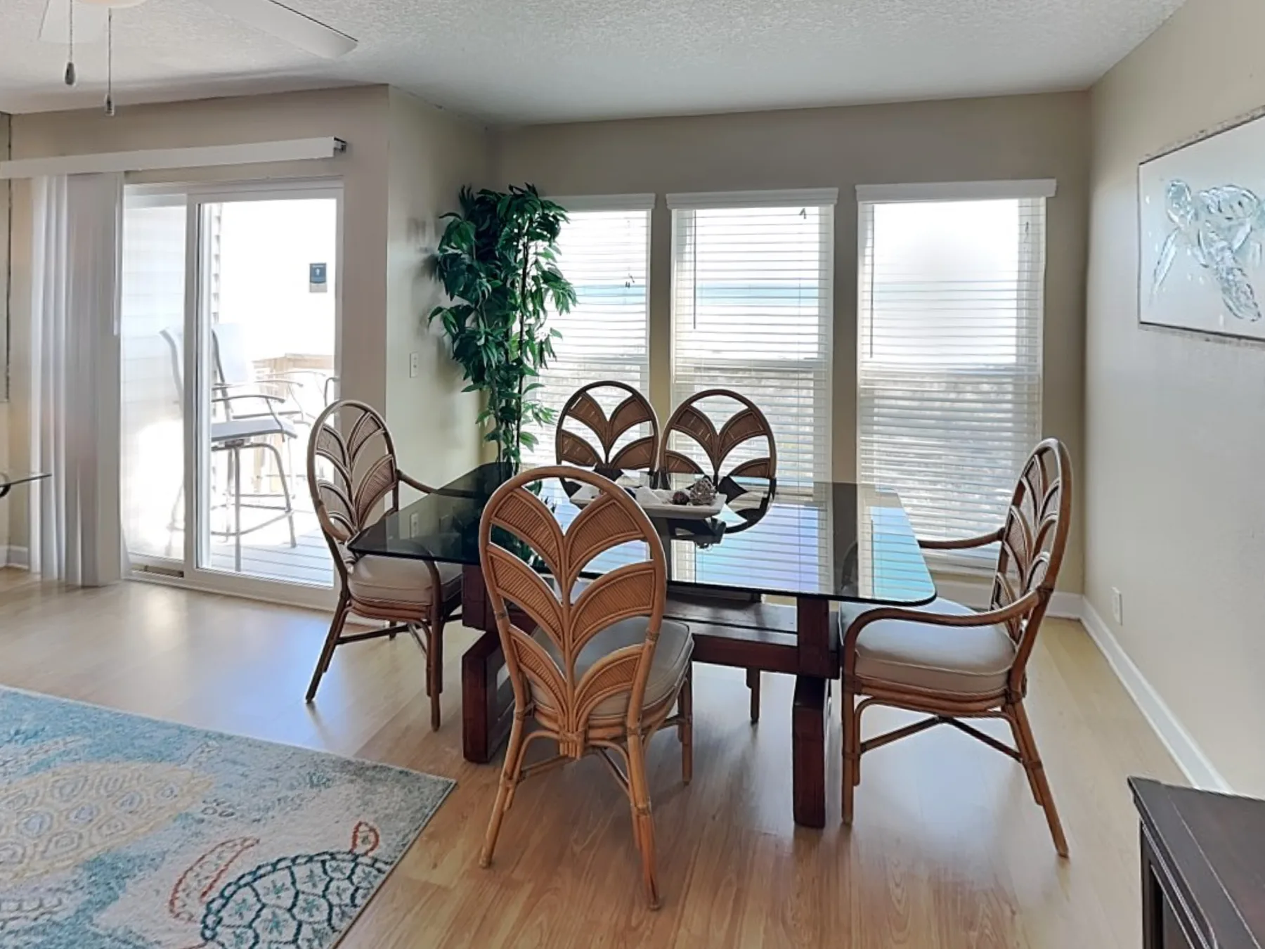 A dining area with a glass table and seating beside large windows.