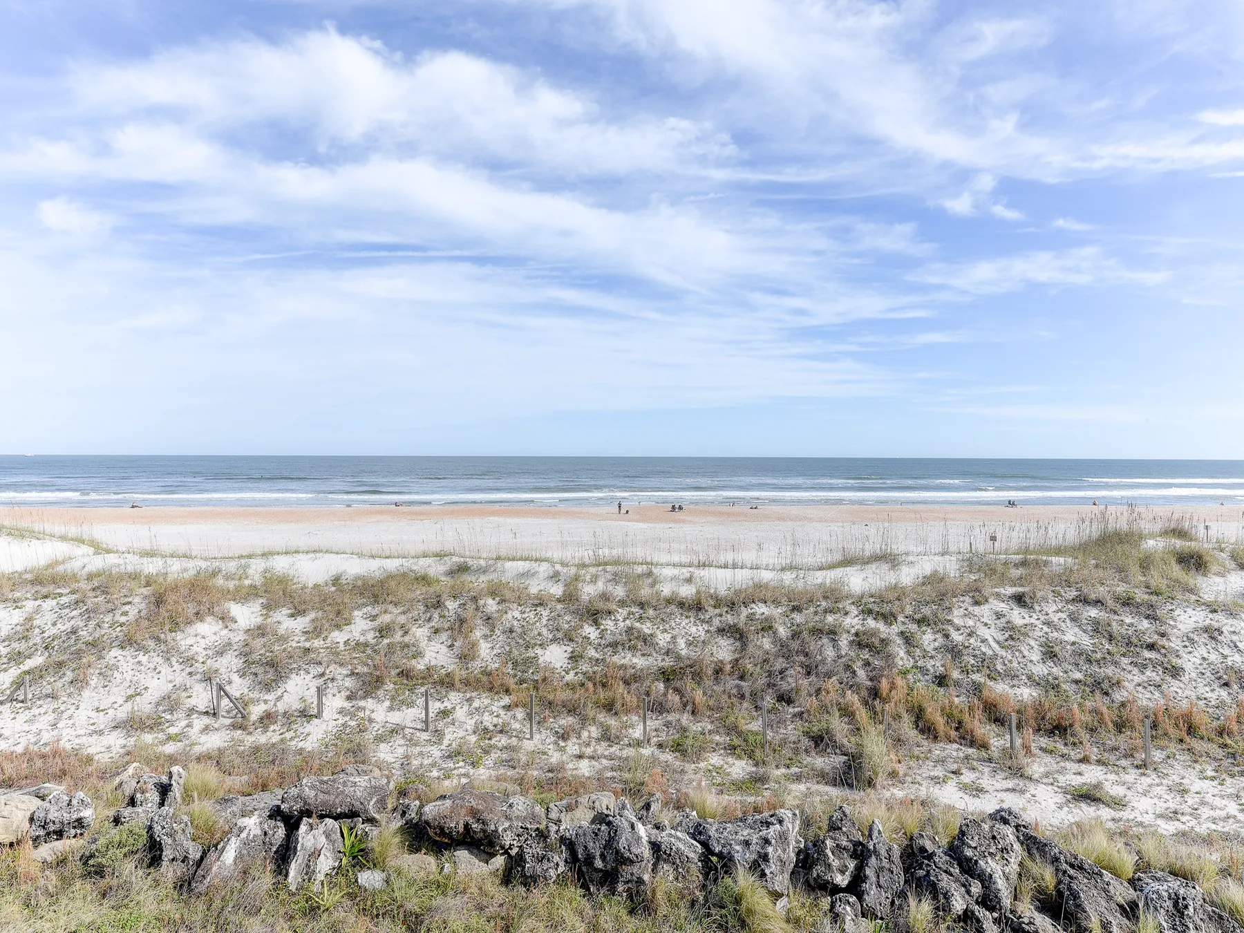 A sandy beach and ocean stretch beneath a cloudy sky.