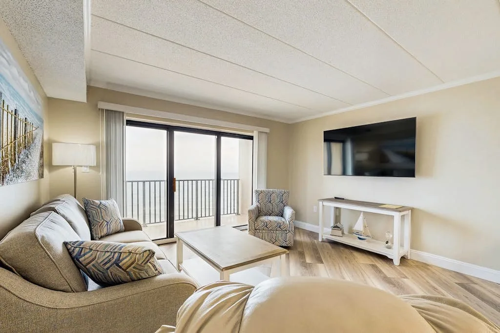 A living room with seating, a coffee table, and a wall-mounted television.