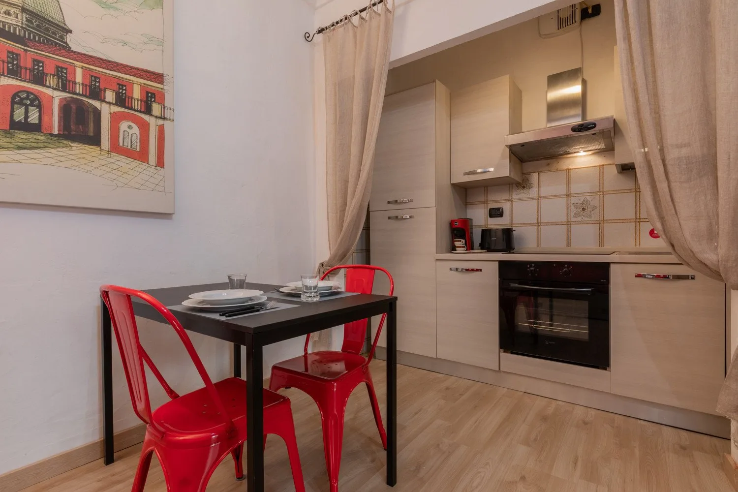 Un comedor con asientos rojos junto a una cocina compacta.