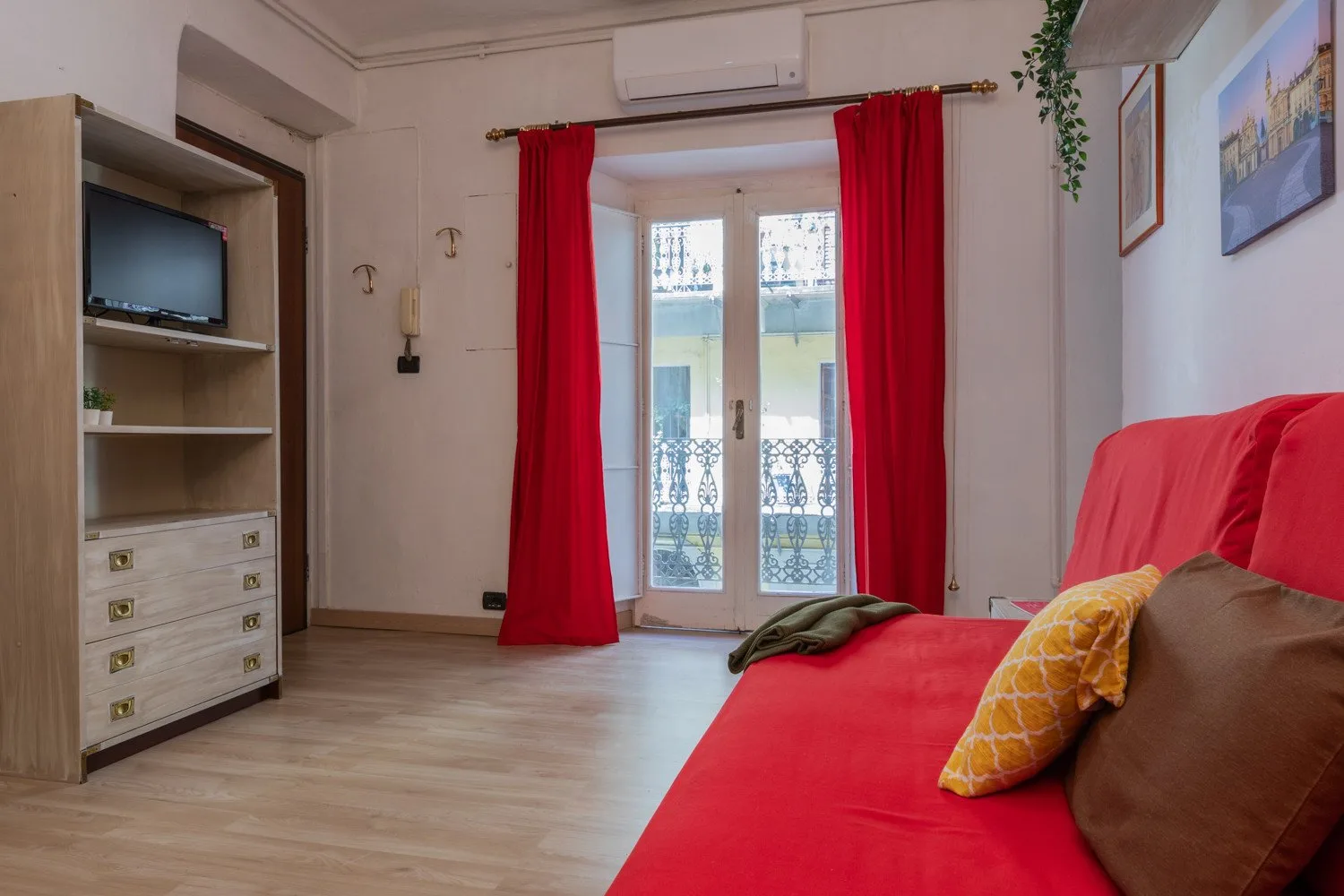 Un dormitorio con ropa de cama y cortinas rojas junto a puertas de cristal.