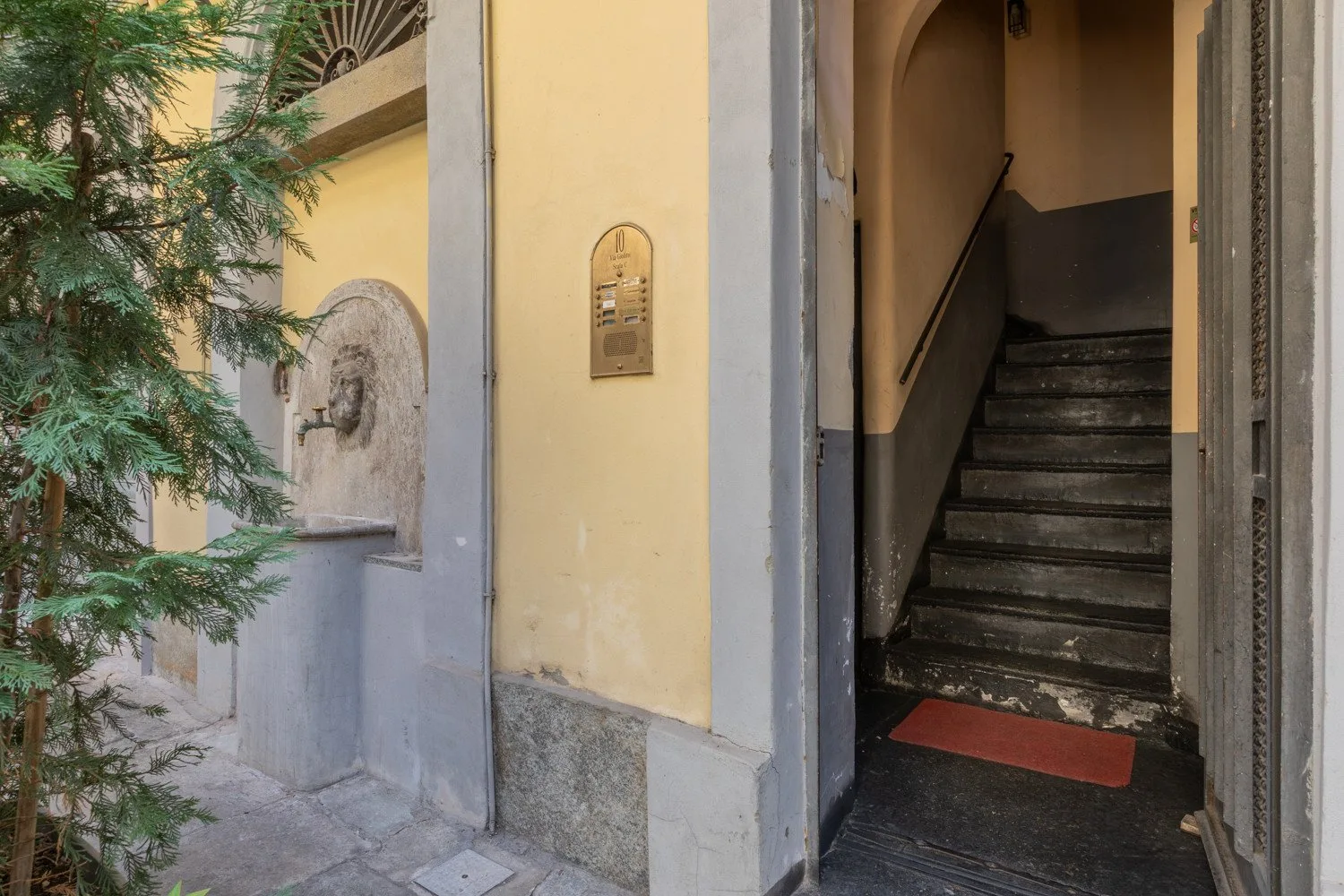 Una entrada abierta deja ver una escalera con peldaños oscuros.