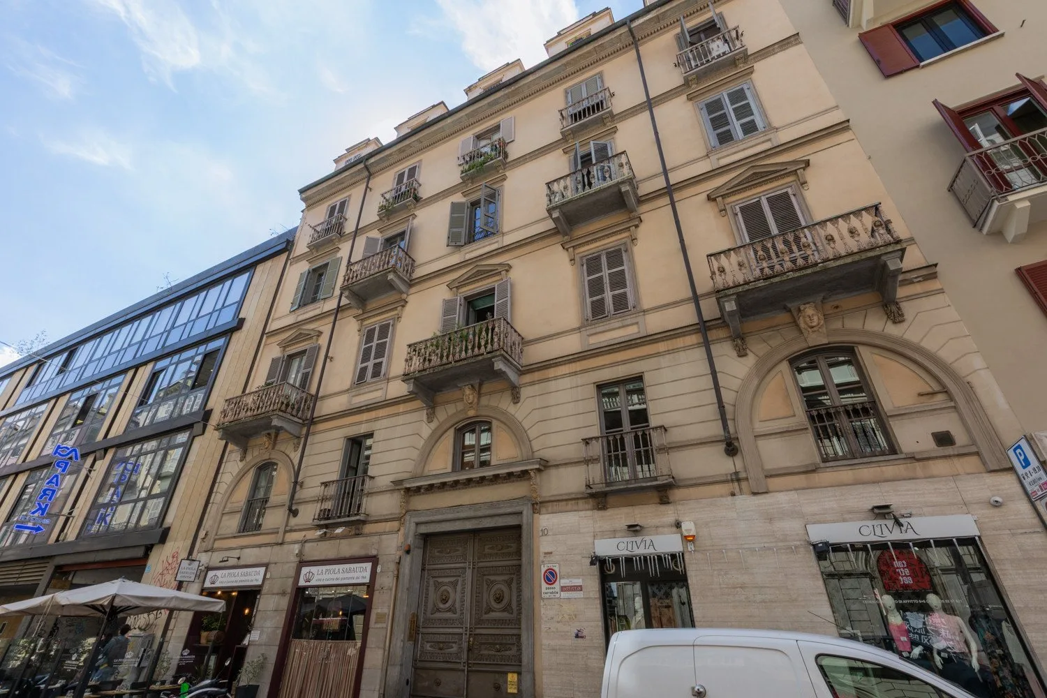 Una fachada urbana de varios pisos con balcones y tiendas en la planta baja.