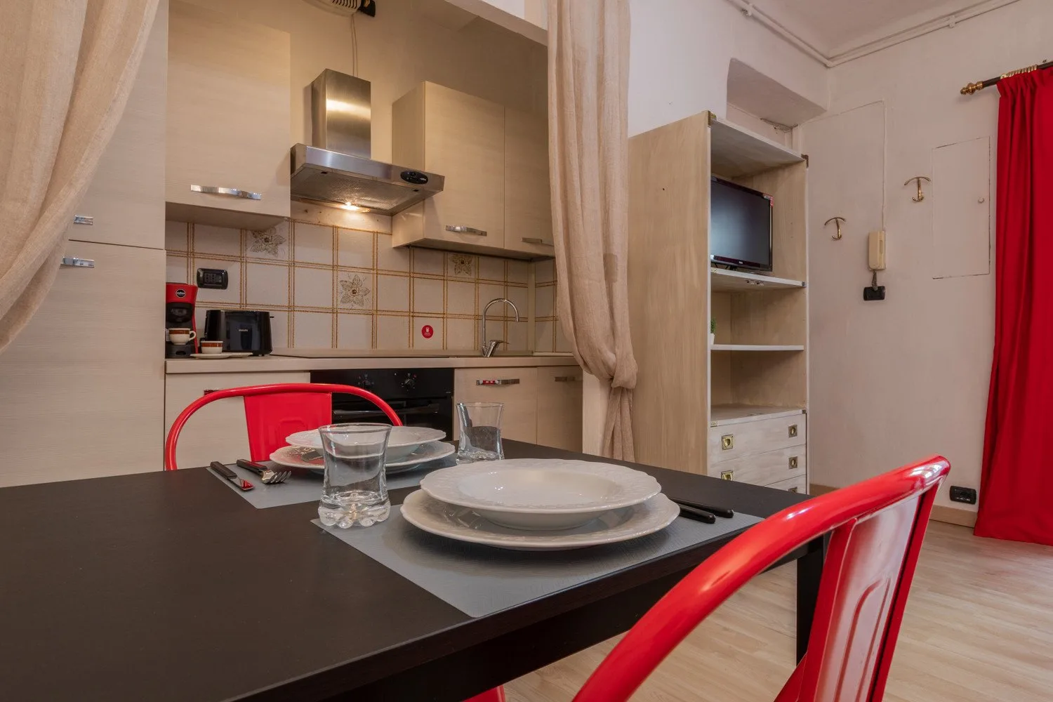 Un comedor con asientos rojos da a una cocina compacta.