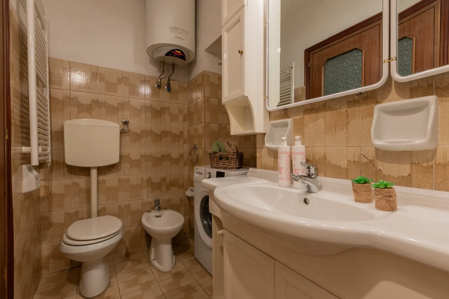Un baño alicatado con lavabo, inodoro, bidé y lavadora.