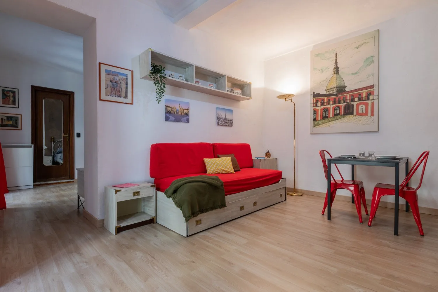 Una sala de estar con un sofá rojo y una pequeña mesa de comedor.