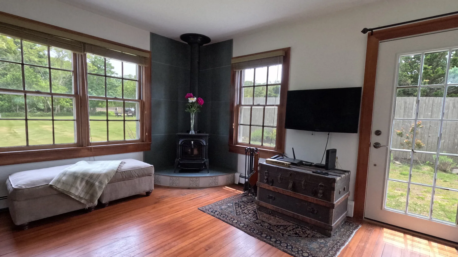 Una sala de estar con ventanas grandes, una estufa de leña y un televisor.