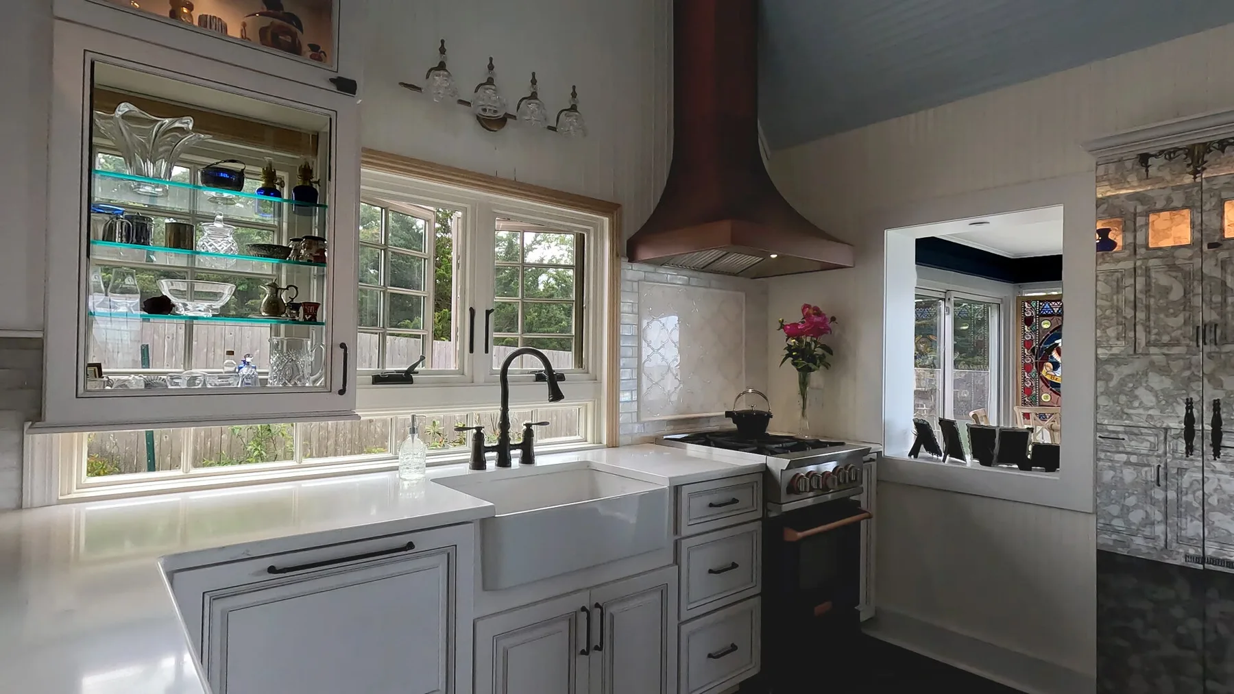 Una cocina luminosa con un fregadero amplio bajo varias ventanas.