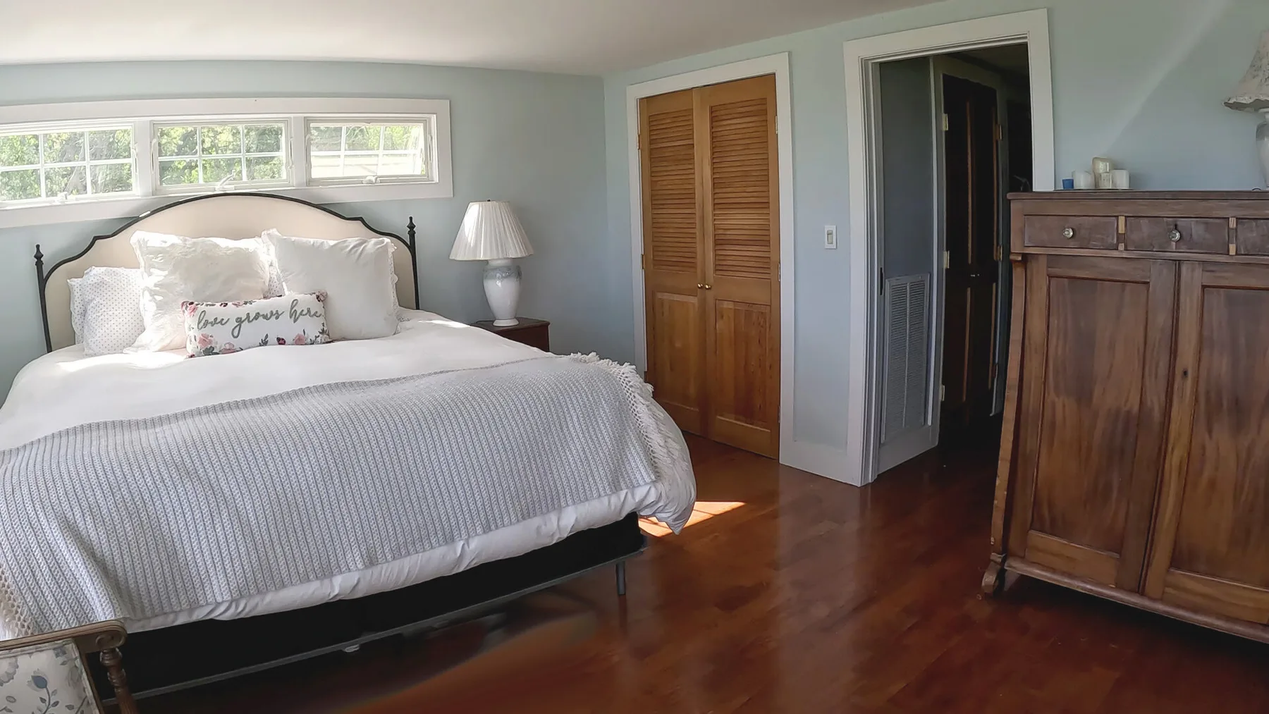 Un dormitorio con una cama, puertas de armario de madera y un mueble grande de madera.